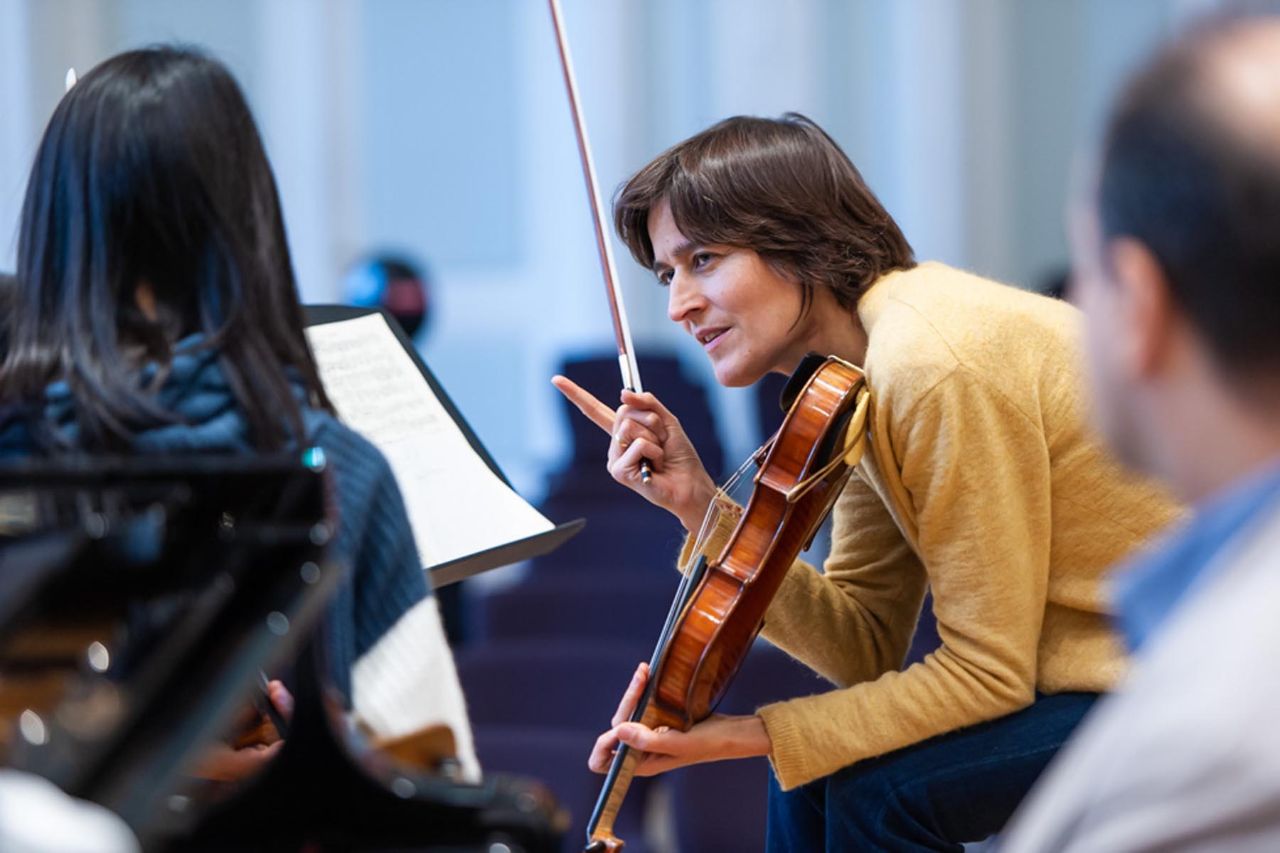 Eine Dozentin für Violine spricht mit einer Studentin über ein Werk.